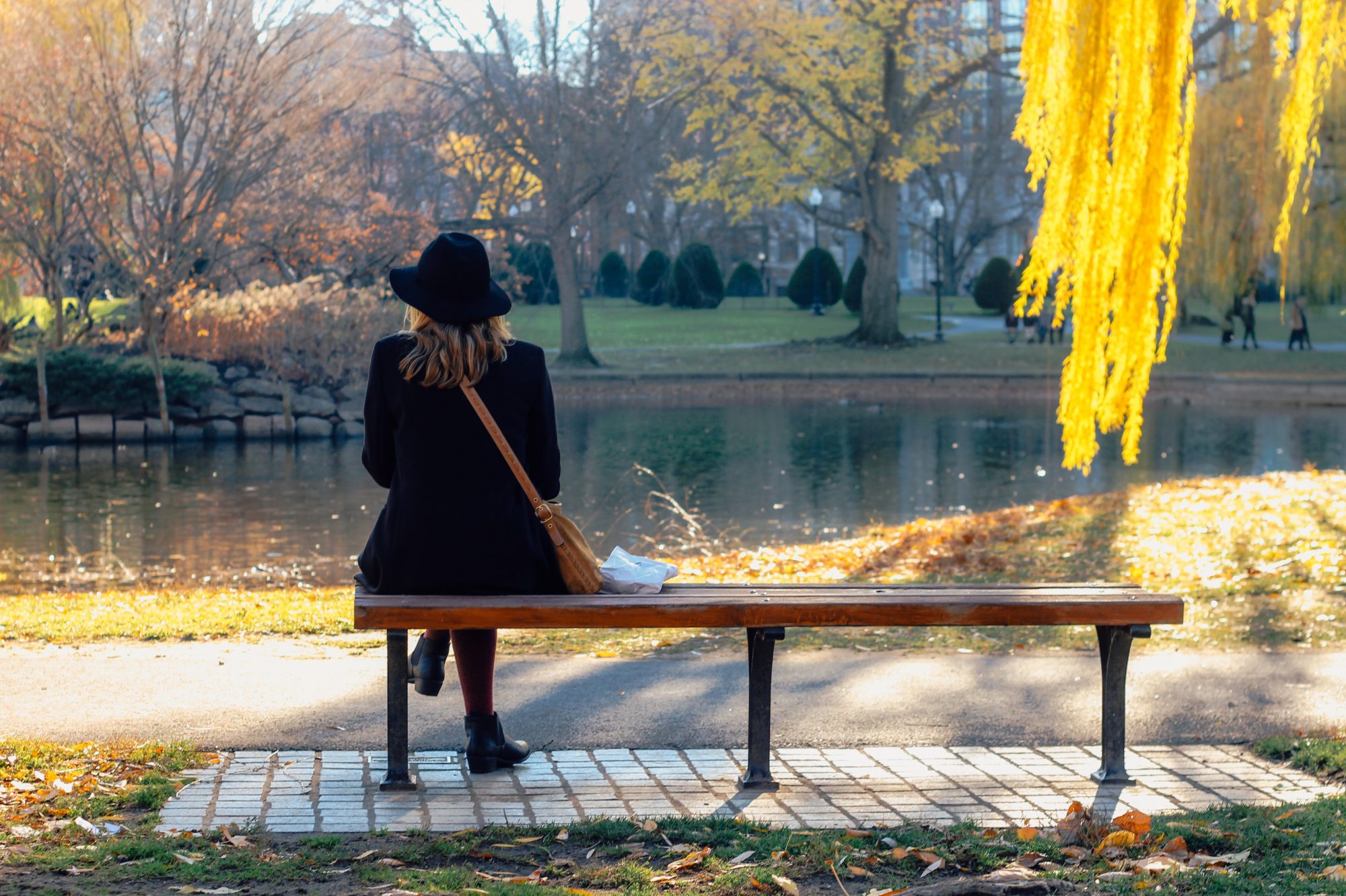 Frau sitzt im Herbst auf einer Bank