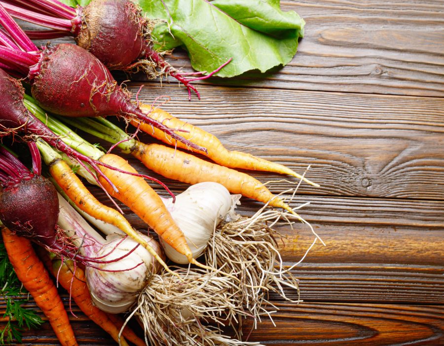 Vegetarian background of fresh organic beetroots green garlic and carrots on kitchen wooden rustic table